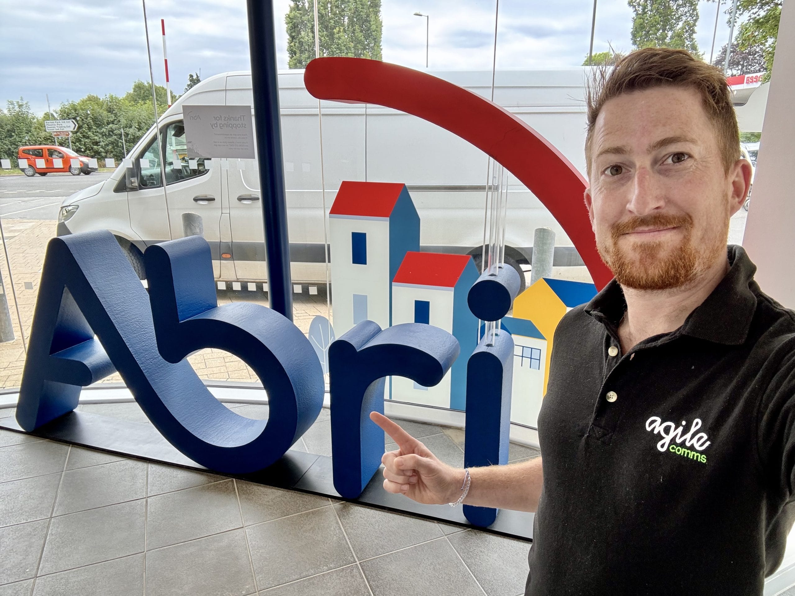 Ollie at the Abri office in front of their logo sign